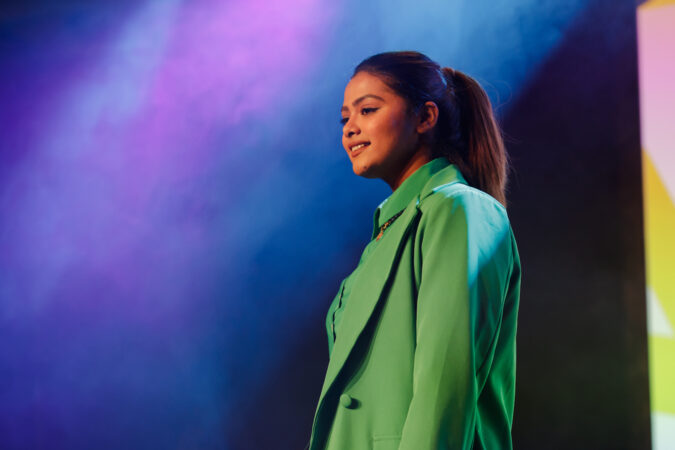 Woman wearing a green suit modelling for an event.